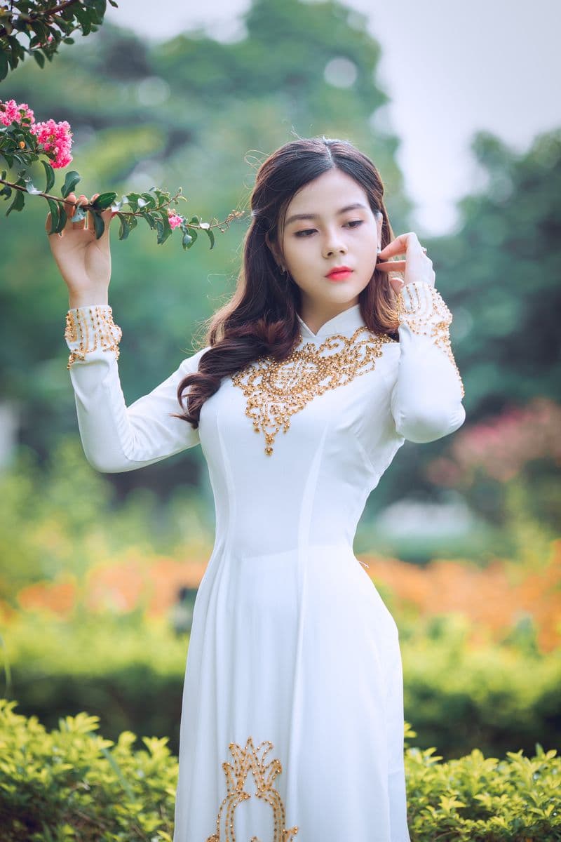 Woman in an elegant white festive dress holding a rose