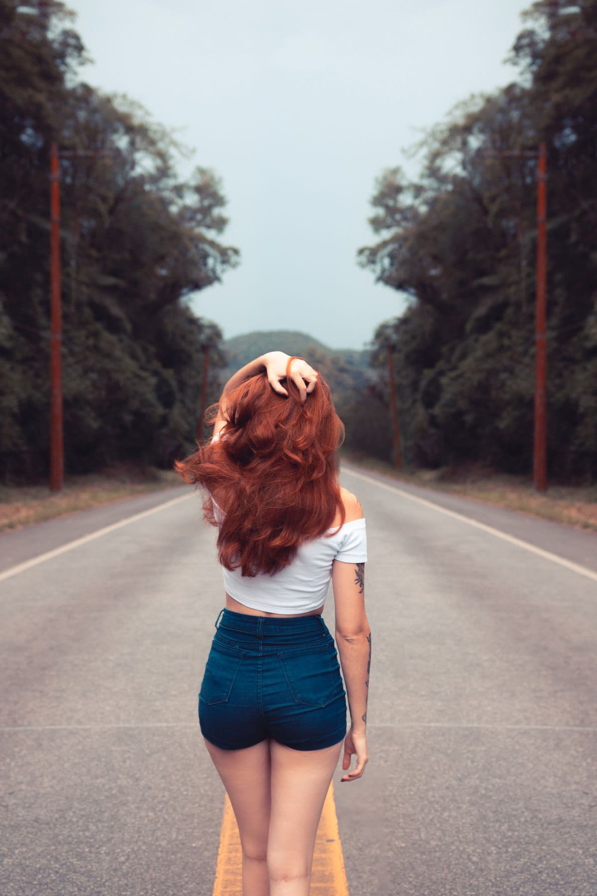 Woman in casual summer attire walking down a tree-lined road